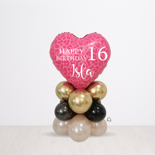 Pink heart-shaped balloon with 'Happy Birthday Isla' text, surrounded by gold, black, and pearl balloons on a white background.