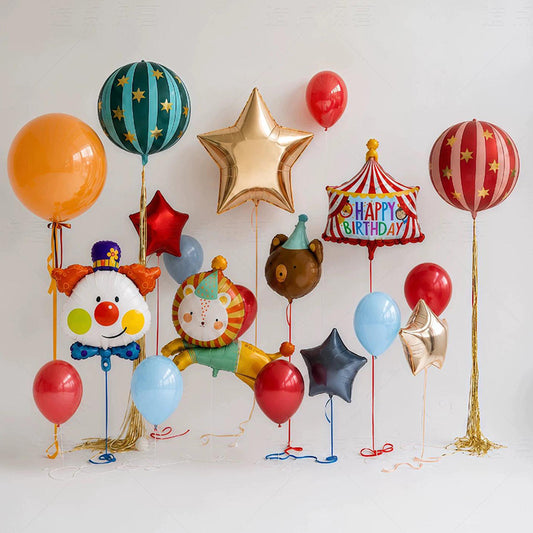 A set of colorful circus and birthday party balloons arranged against a plain white background, including clown-shaped foil balloons, a star-shaped balloon, a striped balloon, a red and gold balloon, and several solid color balloons.