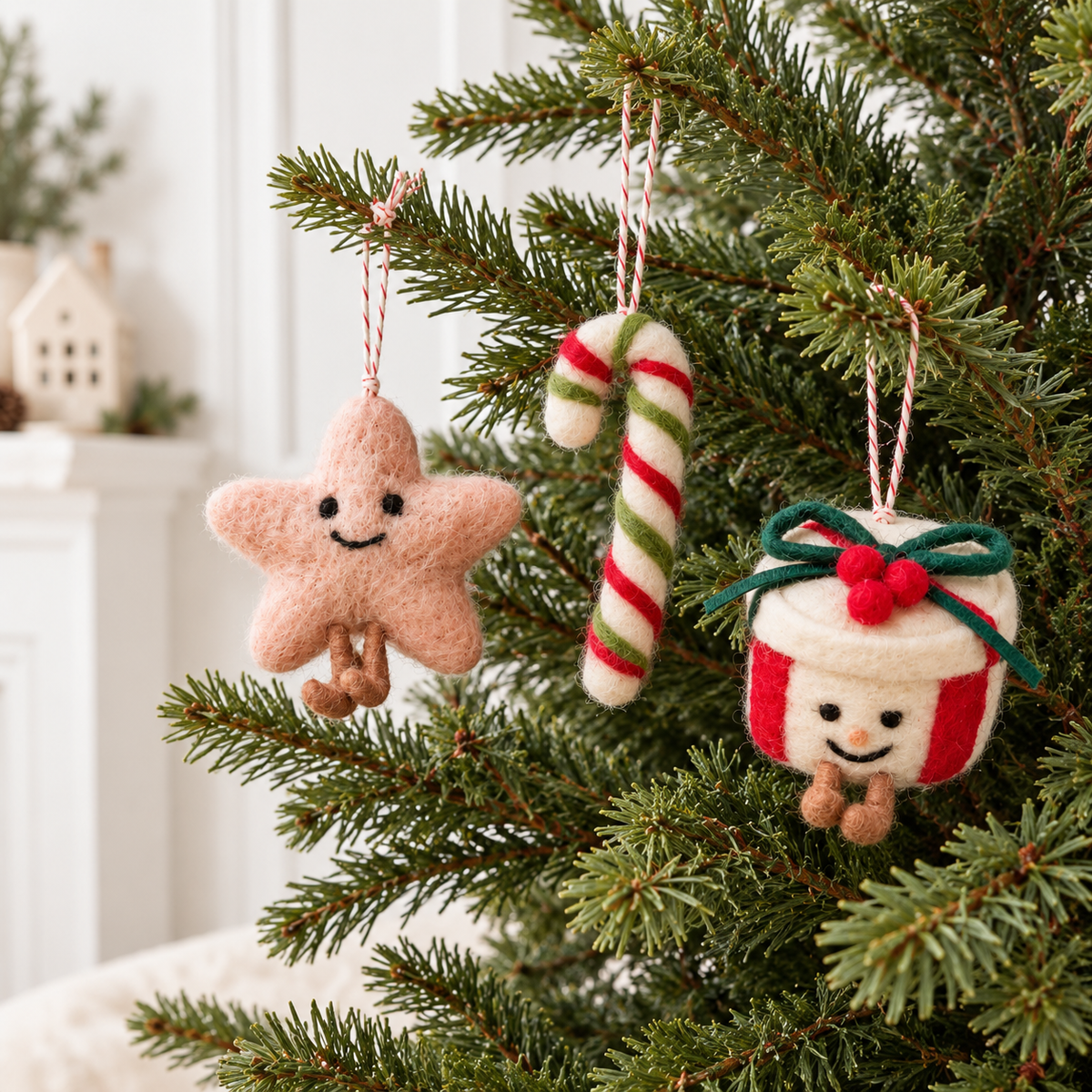 Felted wool star, candy cane and present decorations hanging on a Christmas tree with red-and-white twine loops